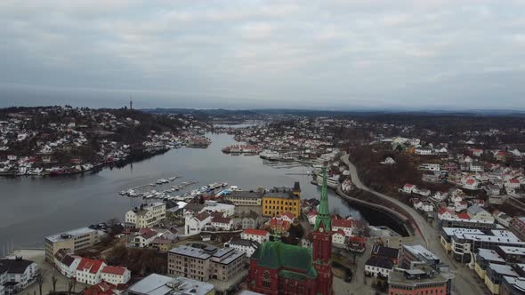 Arendal Norway - Flying above city center with trinity church and Tyvholmen while looking west towar