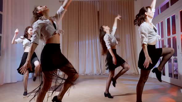 Four Girls in Black Skirts and White Shirts are Dancing Indoors