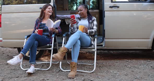 Multiracial women friends having fun camping with camper van
