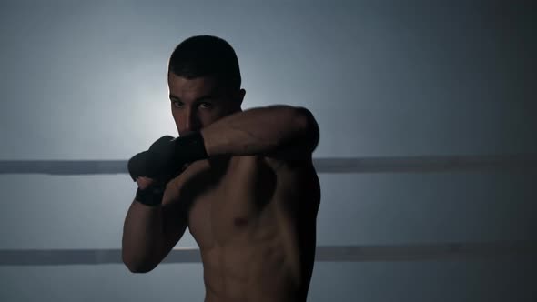 Professional Male Kickboxer Training Alone Indoors in Modern Gym Inside a Boxing Ring