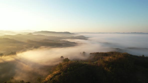 4K aerial view over a misty mountainous area. The great golden sun in the morning
