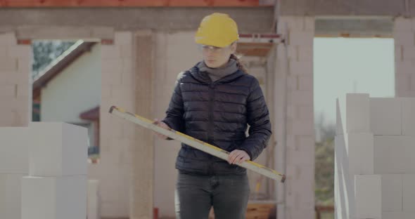 Female Supervisor Examining Concrete Wall with Level