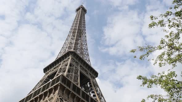 The Eiffel tower symbol of Paris and France against  cloudy blue sky slow pan 4K 3840X2160 30fps Ult