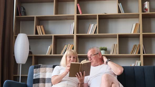 Happy Grandfather and Grandmother Reading Book Enjoying Leisure Time and Hobby Together at Home