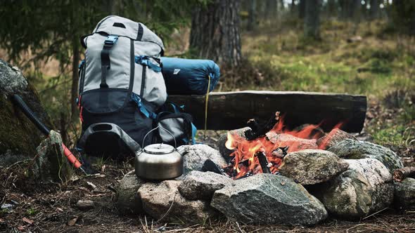 Backpack and Metal kettle on a campfire in the forest