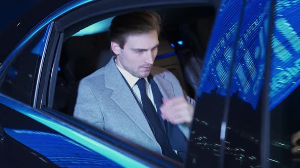 Slow Motion Young Businessman Sitting in a Moving Car and Using Laptop Man Top Manager in a Suit is