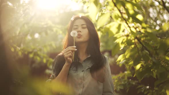 Asian Woman Blow on Dandelion at the Sunset