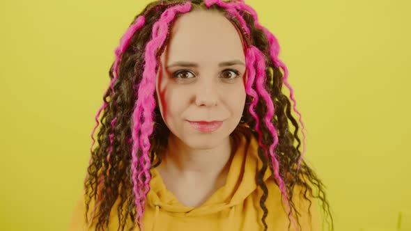 Young Beautiful Woman with Curly Hairstyle Smiling and Winking on Yellow Background