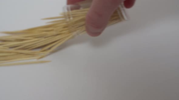 Hand Pours Toothpicks Onto a White Surface From a Jar