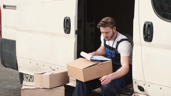 Delivery Driver Checking His List of Parcels