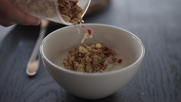 Slow Motion Pour Granola Over Yogurt in White Bowl