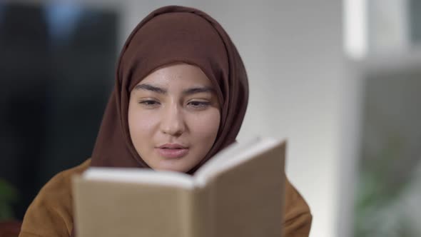 Closeup of Engrossed Absorbed Middle Eastern Young Woman Reading Book Smiling and Looking at Camera