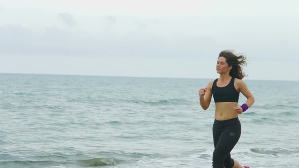 Serious Young Woman With Concentrated Face Expression Running Along Sea Beach