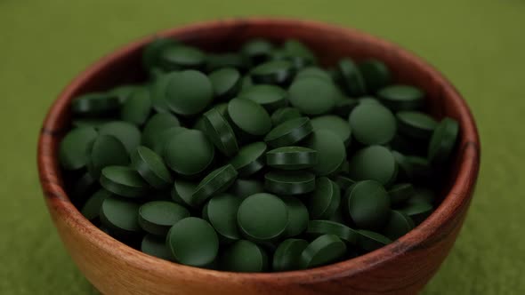 superfoods Spirulina, chlorella supplement green pills in wooden bowl