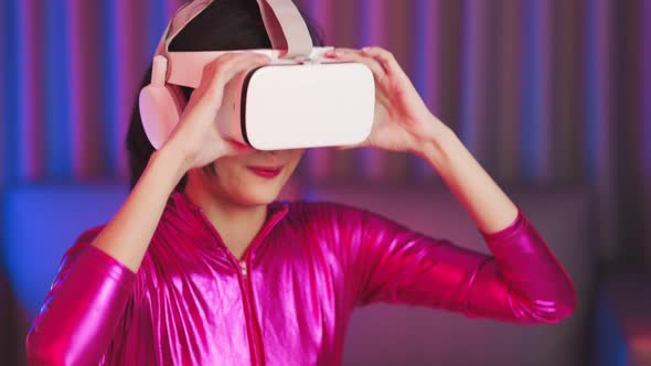 Young asian woman is using virtual reality headset. Neon light studio portrait