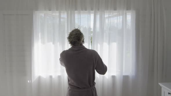Senior man drawing the curtains at home