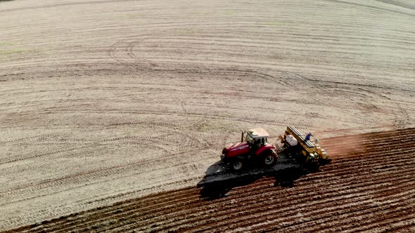 Tractor with seeder in the field. Sowing of corn, Maize in soil, with pneumatic sowing machine durin