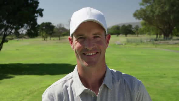 Caucasian male golfer smiling at camera on a golf course