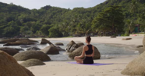 Woman Seats in Lotus Pose, She Meditating Lonely on Yoga Mat at Tropical Beach