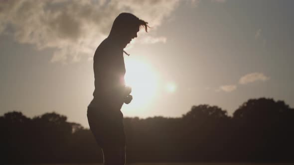 Man In Park Skipping Rope To Keep Fit With The Dying Sun Behind Him In Slow Motion