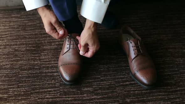 Man Ties Up Shoelaces on Brown Leather Shoes