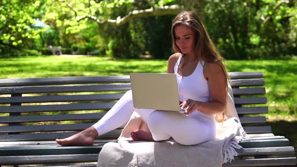 Well Looking Middle Aged Woman Typing on Laptop Keyboard Outdoors on Bench in the Park