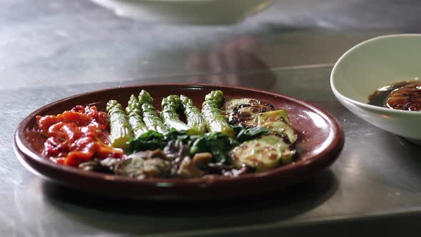 An asparagus and roasted red pepper salad, with a fried mullet fish that enters and exists out of sc