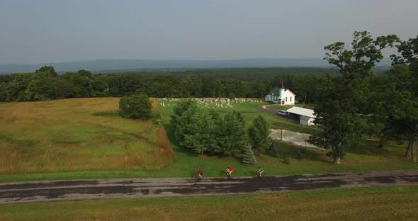 Aerial views of family bicycling along pastoral country roads.