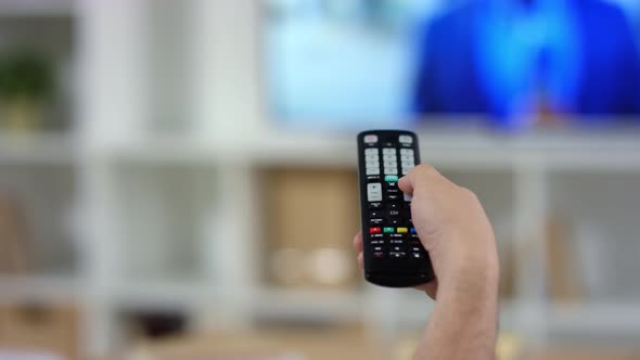 Hand of Man Using TV Remote Control at Home