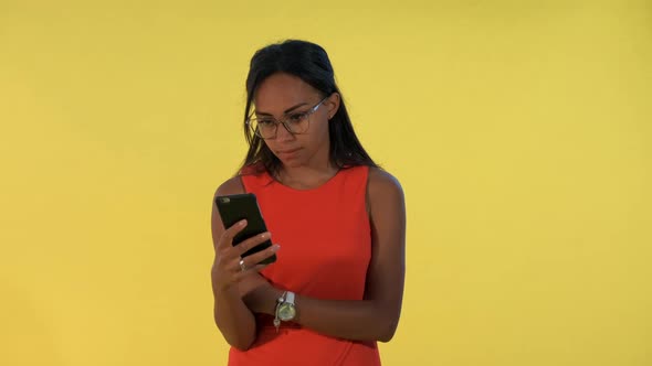 Multiracial Pretty Woman Looking Surprised at Smartphone on Yellow Background