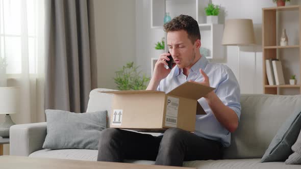 Man Sitting on Sofa with Opened Parcel Express Complaints to Seller or Courier on the Phone About