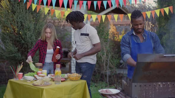 Three Positive Multiracial Friends Preparing Picnic Table in Slow Motion Outdoors