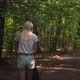 Back view of a mother walking with a stroller in the dark woods. - VideoHive Item for Sale