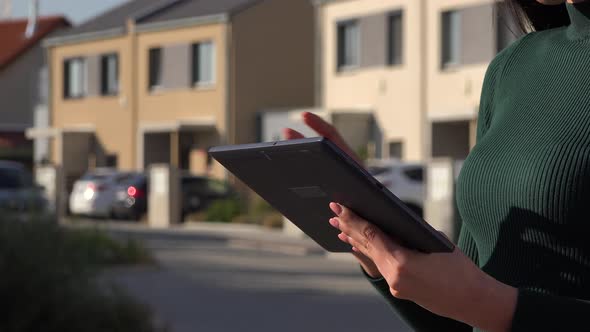 A Young Asian Woman Works on A Tablet in A Suburban Area