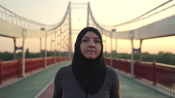 Healthy Arab Woman in Hijab Running Across Bridge