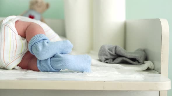 Tiny Cute Newborn Babies Feet In Blue Socks Early First Days Of Life On White Background