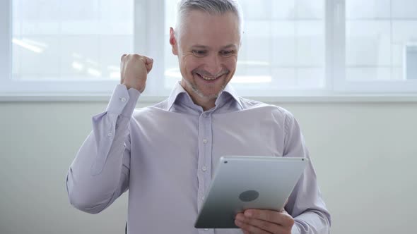 Middle Aged Man Excited for Success while Using Tablet