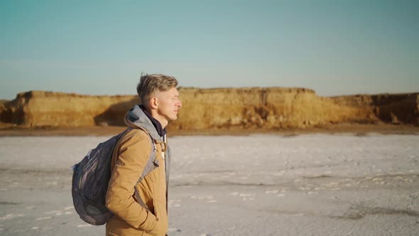 Slow Motion Shot of Young Adult Man Walking at Lake Coast with White Salty Flats and Clay Shore