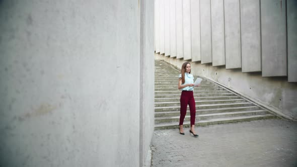 Businesswoman Reading Business Documents Outdoors. Female Worker Walking for Job