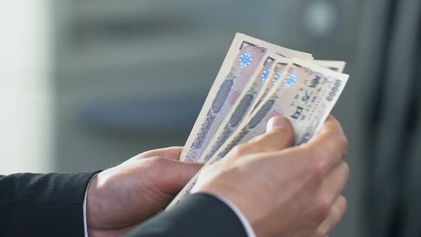 Male Hands Counting Money Exchanging Japanese Yen at Bank Branch Finance