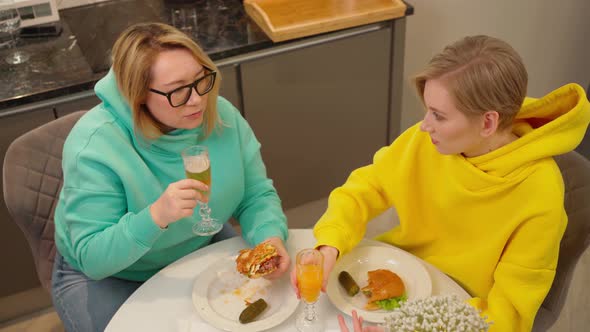 Two Women in Love Spend Time Together at Home Eat Burgers and Drink Drinks From Beautiful Glasses