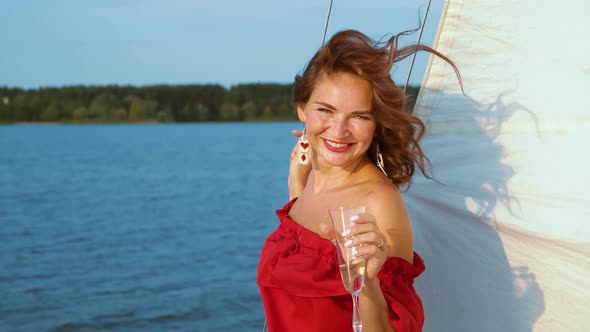 Pretty Girl in Red Dress Relaxing and Drinking Wine on Sailing Boat