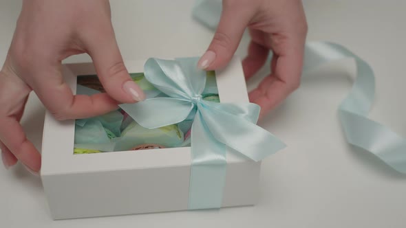 Confectioners Hands Decorating Gift Box with Macaron Cookies