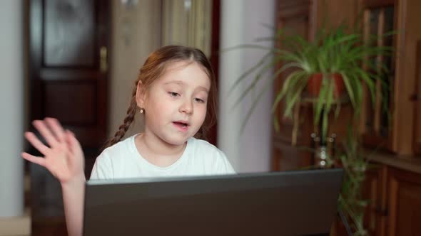 Young, beautiful little girl studying working in front of a computer at home