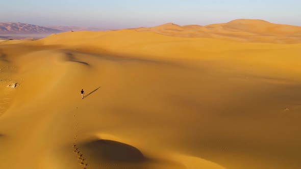 Aerial view of a man walking on dunes during the sunset, U.A.E.