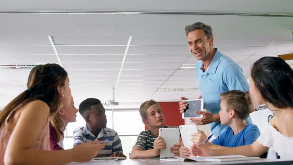 Teacher assisting schoolkids on digital tablet