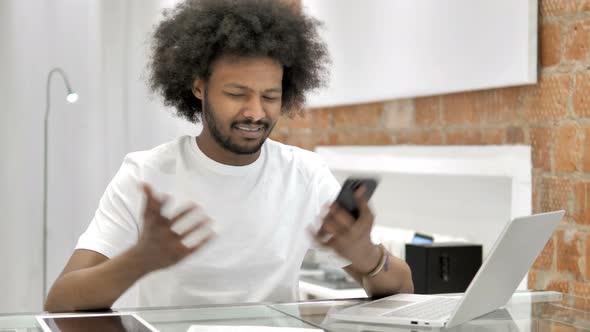 African Man Reacting To Loss on Smartphone