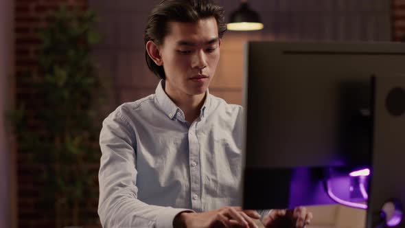 Focused Asian Man Working on Commercial Report on Website