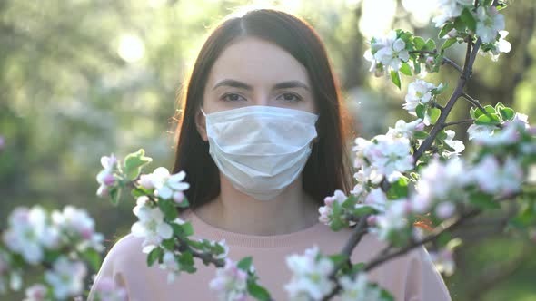 Woman in Medical Mask in Apple Blossoms in Spring