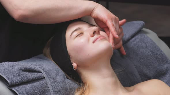 Young Woman in a Chic Beauty Salon Gets a Facial Massage and Beauty Treatments for Skin Care